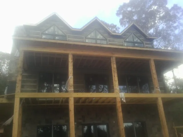 Dormers and porch framing on a large log home under construction — Roof Coating work by our crew in Wausaukee