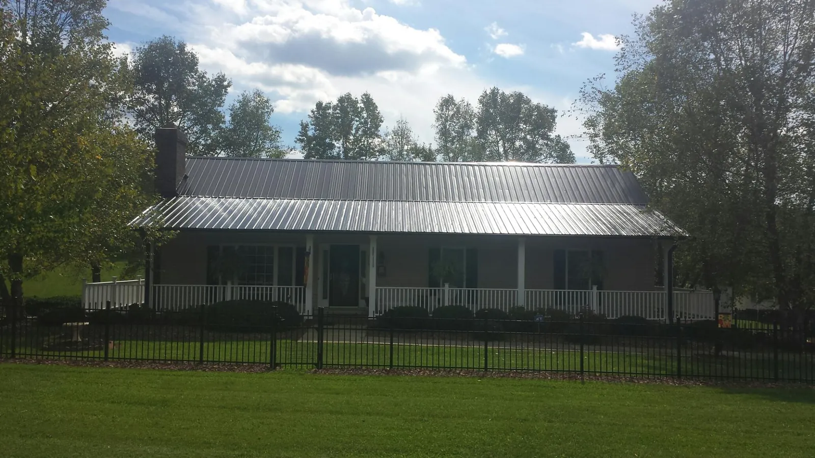 Gray metal roof on a brick ranch with a full width front porch — Gutter Guard Installation work by our crew in Wausaukee