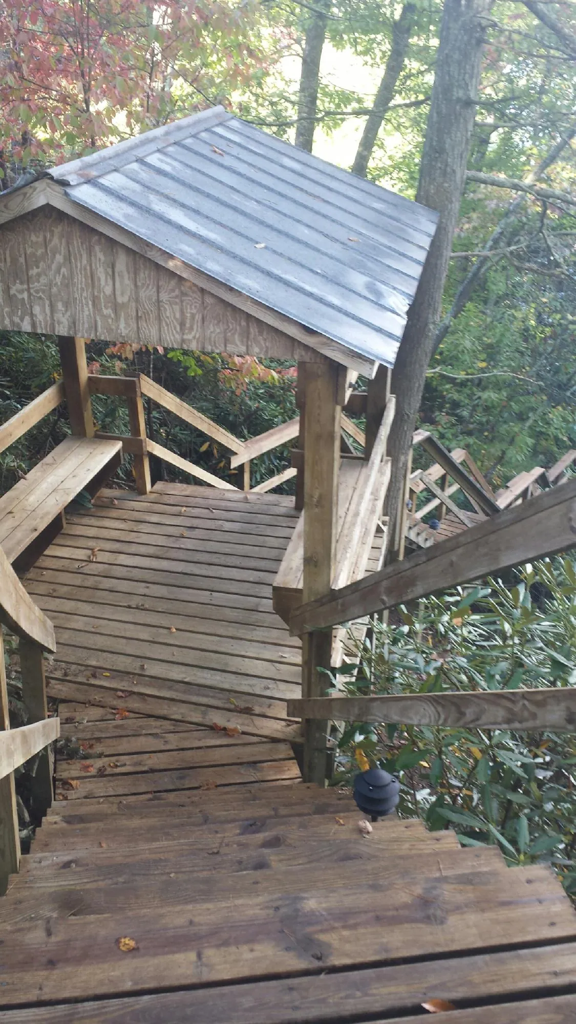 Metal roofed shelter over wooden steps on a wooded walkway — Skylight Repair & Installation work by our crew in Wausaukee